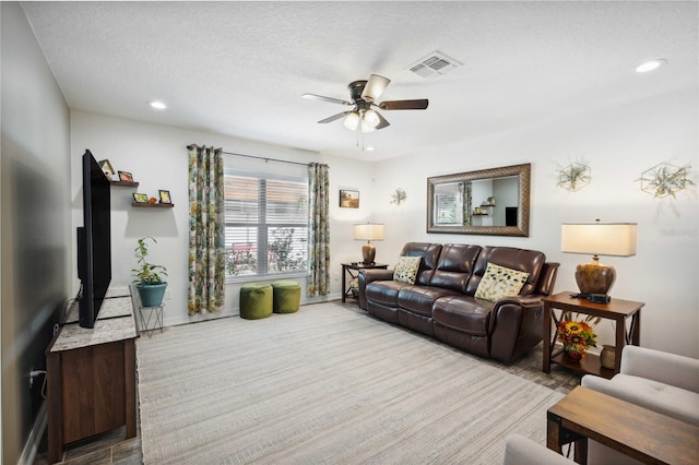living room featuring baseboards, recessed lighting, a textured ceiling, visible vents, and ceiling fan