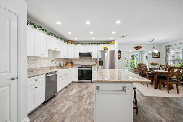 kitchen with tasteful backsplash, visible vents, a kitchen island, appliances with stainless steel finishes, and wood finished floors