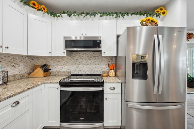 kitchen with white cabinets, decorative backsplash, appliances with stainless steel finishes, and light stone countertops