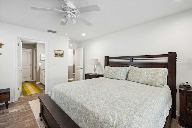 bedroom featuring ensuite bath, visible vents, recessed lighting, wood finished floors, and baseboards