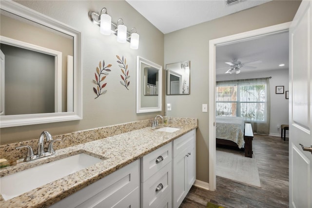 ensuite bathroom featuring a sink, double vanity, wood finished floors, and a ceiling fan