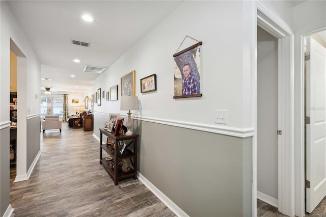 hall featuring wood finished floors, baseboards, visible vents, and recessed lighting