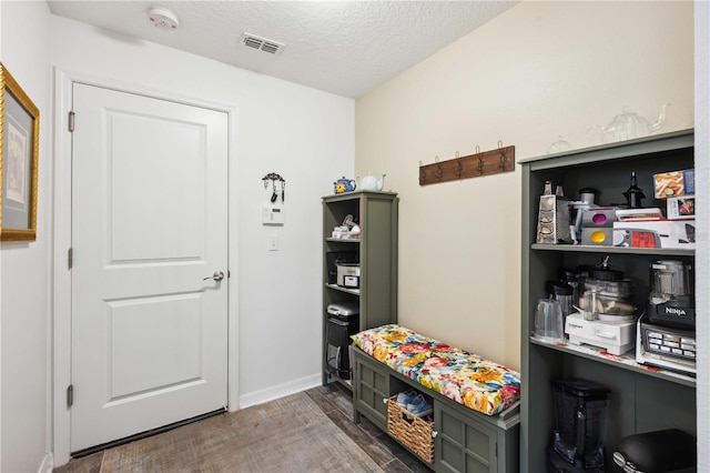 mudroom featuring a textured ceiling, wood finished floors, baseboards, and visible vents