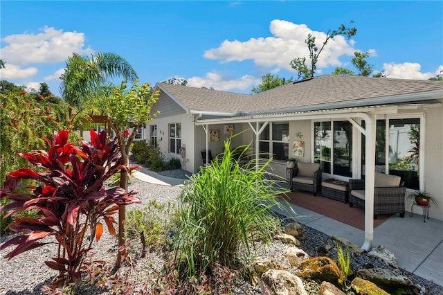 rear view of property featuring a shingled roof and stucco siding