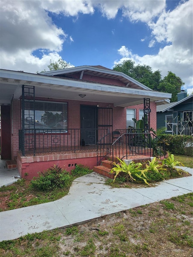 bungalow-style home featuring a porch and brick siding