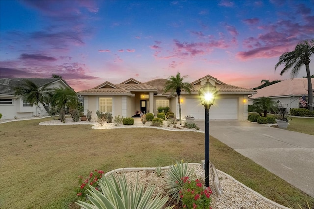 view of front facade featuring a tiled roof, stucco siding, a front yard, an attached garage, and concrete driveway