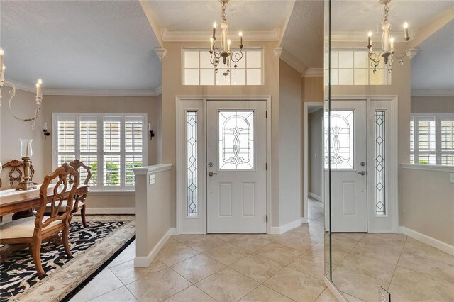 foyer entrance with a notable chandelier, ornamental molding, baseboards, and a wealth of natural light