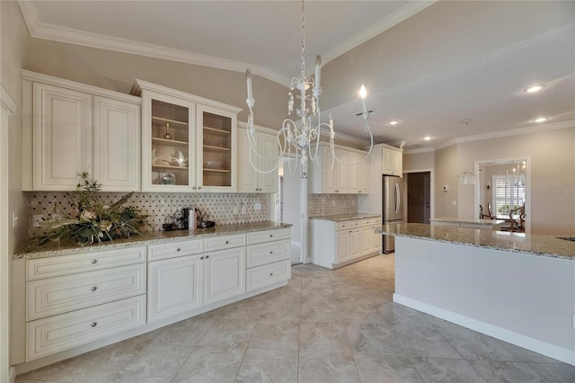 kitchen with light stone countertops, freestanding refrigerator, crown molding, and backsplash