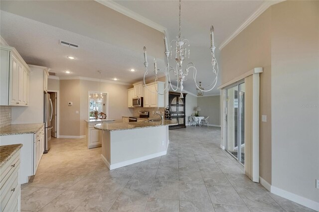 kitchen featuring ornamental molding, a chandelier, stainless steel appliances, decorative backsplash, and a kitchen island