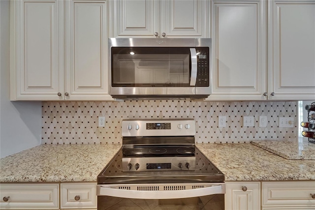 kitchen featuring light stone countertops, backsplash, and appliances with stainless steel finishes