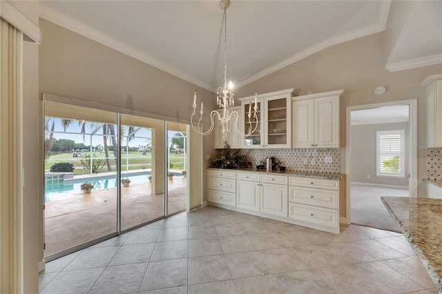 kitchen featuring tasteful backsplash, ornamental molding, light stone counters, glass insert cabinets, and lofted ceiling