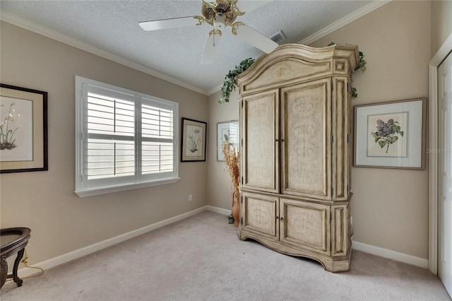 spare room with a textured ceiling, light colored carpet, ornamental molding, a ceiling fan, and visible vents