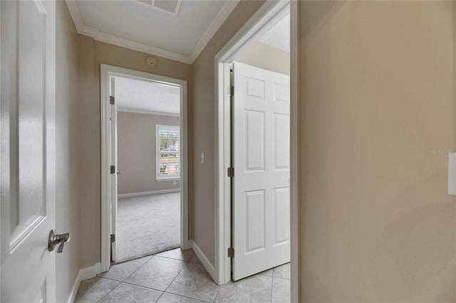 hall featuring visible vents, baseboards, ornamental molding, light tile patterned flooring, and light carpet