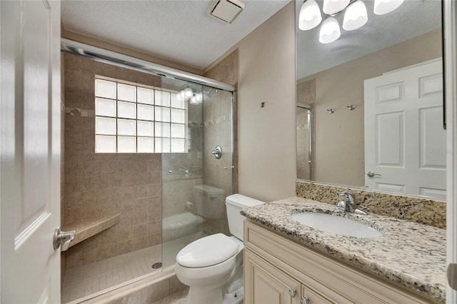 bathroom with visible vents, toilet, a textured ceiling, vanity, and a stall shower