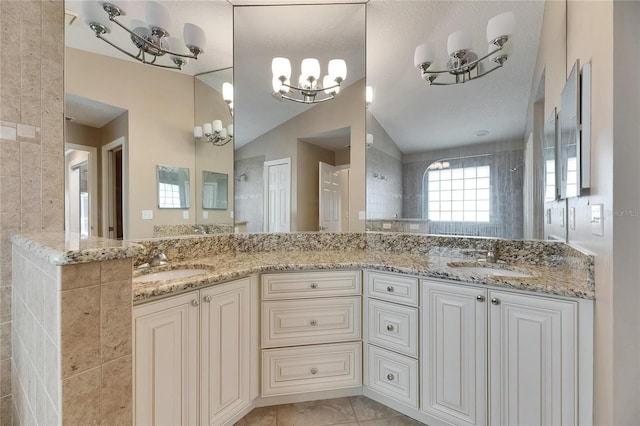 bathroom featuring a sink, tiled shower, an inviting chandelier, and double vanity