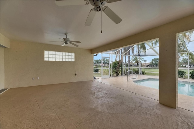 exterior space with a patio area, a ceiling fan, and glass enclosure