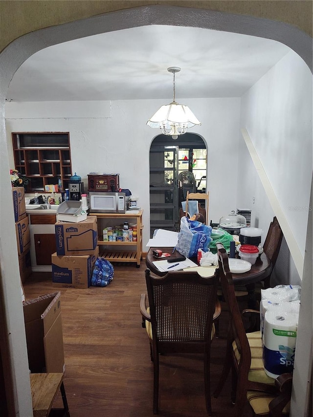 dining room featuring arched walkways, an inviting chandelier, and wood finished floors