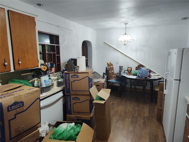 interior space featuring white appliances, brown cabinetry, visible vents, decorative light fixtures, and dark wood-style floors
