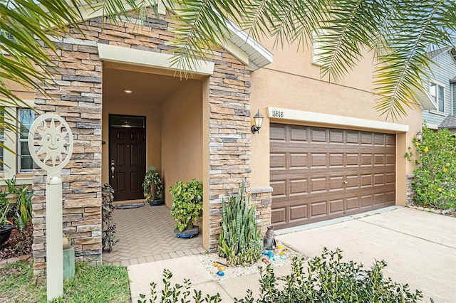 doorway to property featuring concrete driveway, stucco siding, stone siding, and an attached garage