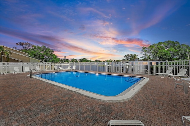 6490 Cape Hatteras Way NE Unit 4, Saint Petersburg, FL 33702 - pool at dusk featuring a community pool, fence, and a patio area