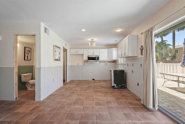 6490 Cape Hatteras Way NE Unit 4, Saint Petersburg, FL 33702 - kitchen with visible vents, stainless steel microwave, white cabinetry, and tile patterned floors