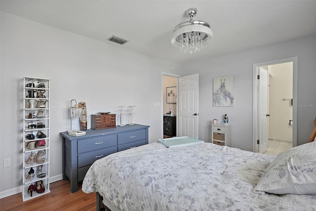 6490 Cape Hatteras Way NE Unit 4, Saint Petersburg, FL 33702 - bedroom with a notable chandelier, visible vents, baseboards, and wood finished floors