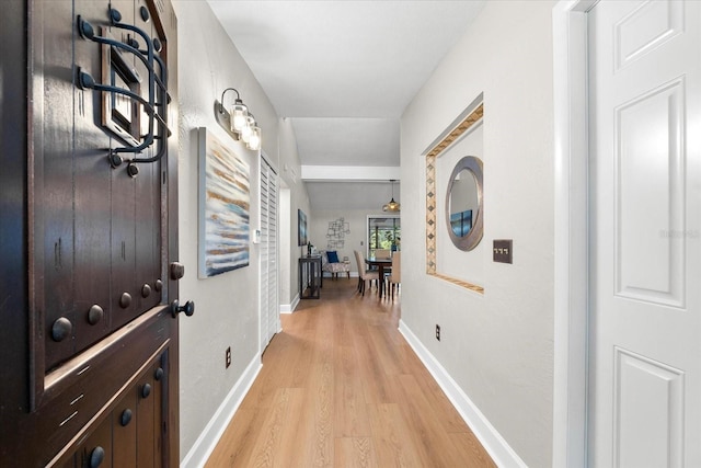 corridor with light wood-style flooring and baseboards