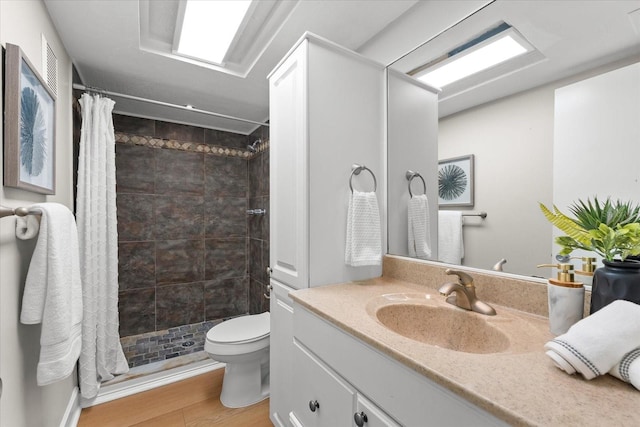 full bath with tiled shower, toilet, wood finished floors, and vanity