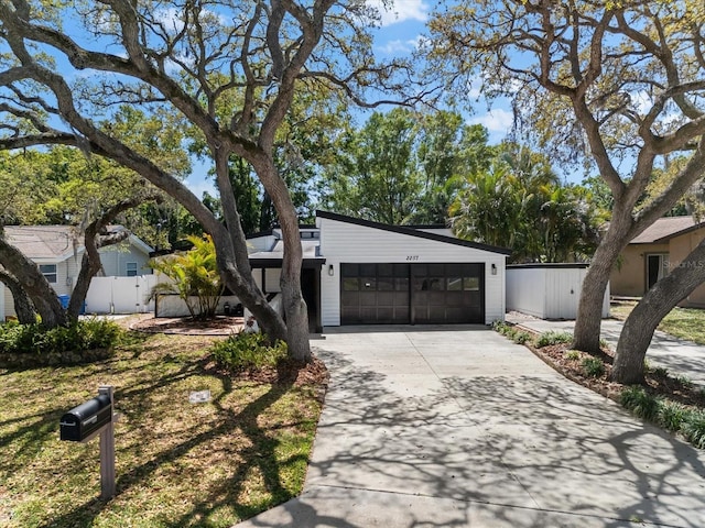 view of front facade featuring concrete driveway, fence, and a garage