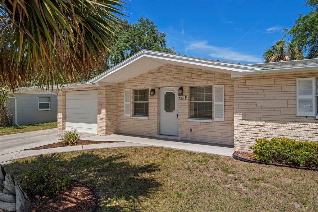 view of front facade with a garage, a front yard, stone siding, brick siding, and concrete driveway