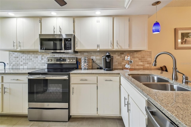 kitchen featuring light tile patterned floors, tasteful backsplash, a sink, hanging light fixtures, and stainless steel appliances