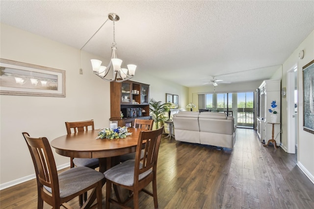 dining room featuring dark wood-type flooring, ceiling fan with notable chandelier, baseboards, and a textured ceiling