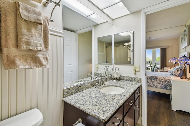 bathroom featuring toilet, vanity, connected bathroom, and wood finished floors