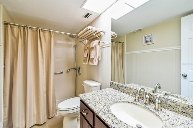 bathroom featuring vanity, visible vents, toilet, curtained shower, and wainscoting