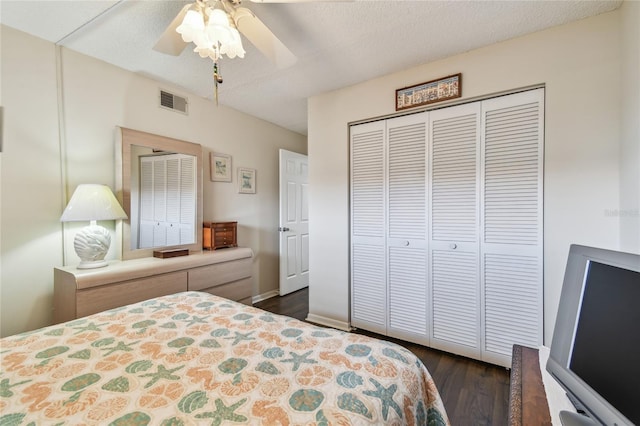 bedroom featuring dark wood-type flooring, a textured ceiling, a closet, a ceiling fan, and visible vents