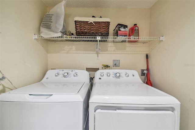 clothes washing area with independent washer and dryer, laundry area, and a textured ceiling