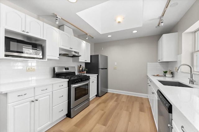 1232 Sedeeva Cir S, Clearwater, FL 33755 - kitchen featuring stainless steel appliances, track lighting, under cabinet range hood, white cabinetry, and light stone counters