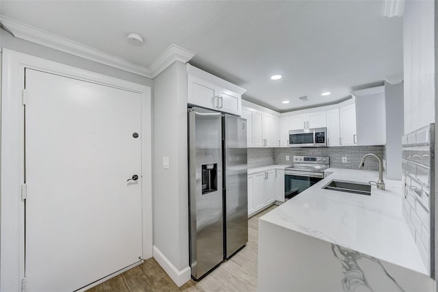 kitchen with a sink, appliances with stainless steel finishes, light wood finished floors, light stone countertops, and backsplash