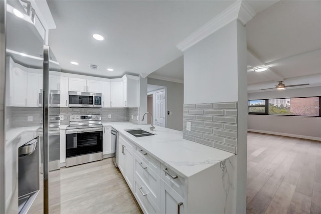 kitchen featuring a sink, ornamental molding, stainless steel appliances, backsplash, and light wood-style flooring