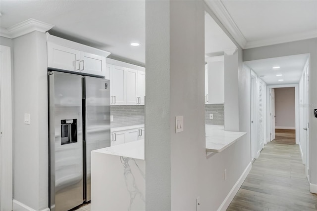 kitchen with ornamental molding, white cabinetry, stainless steel refrigerator with ice dispenser, light wood finished floors, and backsplash