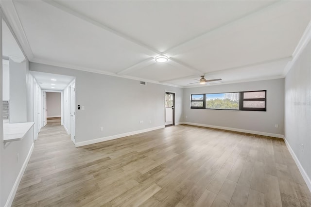 spare room featuring crown molding, baseboards, and light wood-type flooring