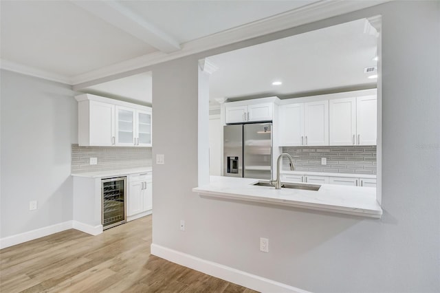 kitchen featuring stainless steel refrigerator with ice dispenser, beverage cooler, a sink, and white cabinetry