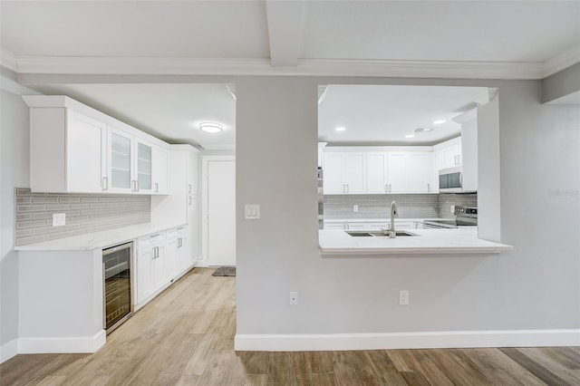 kitchen with white microwave, light wood-style flooring, electric range, beverage cooler, and a sink