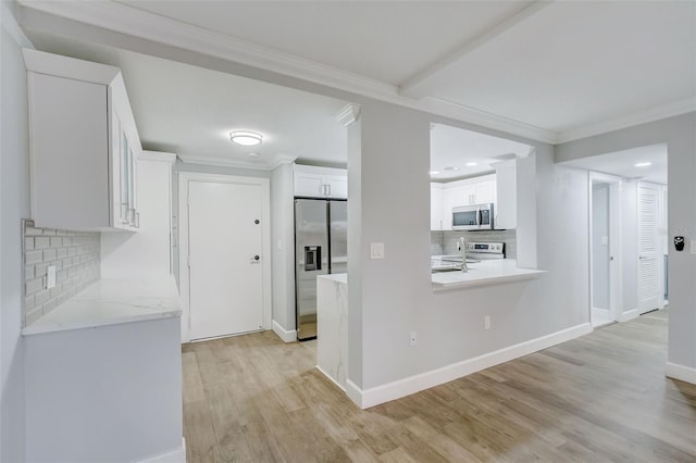 kitchen featuring light wood-type flooring, appliances with stainless steel finishes, ornamental molding, and white cabinets