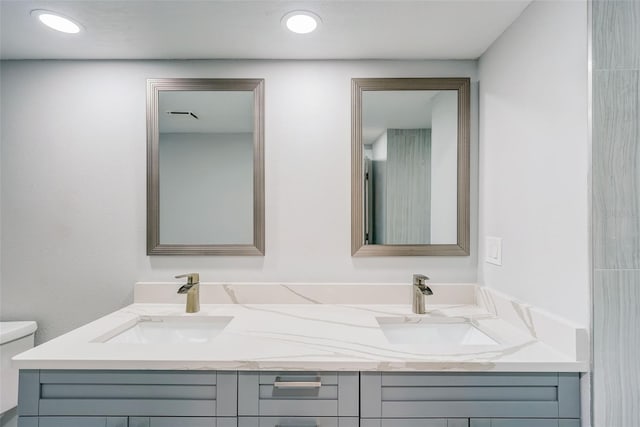 bathroom featuring toilet, double vanity, and a sink