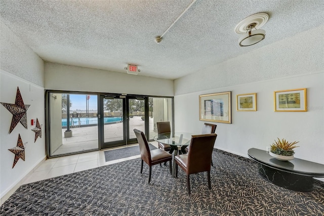 tiled dining room with a textured ceiling, baseboards, and carpet