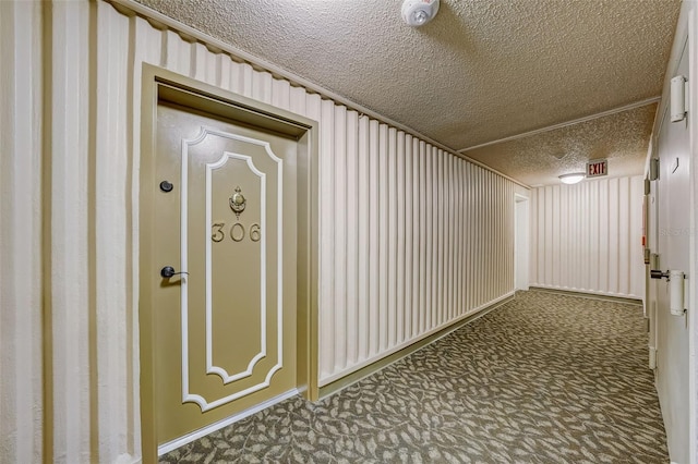 corridor with a textured ceiling and carpet floors