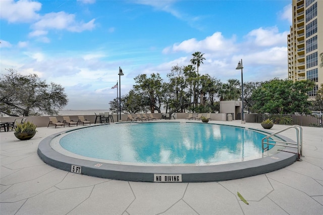 community pool with a patio area and fence