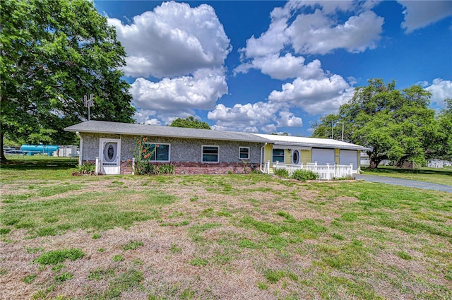 single story home featuring an attached garage, driveway, a front yard, and brick siding