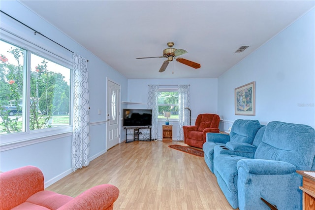 living area with light wood-style flooring, baseboards, a ceiling fan, and visible vents